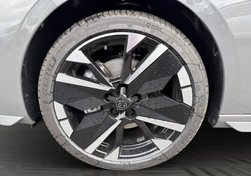 Gros plan sur la roue avant droite gris clair de la Peugeot 308 2026 avec jante noire et argentée au design moderne.