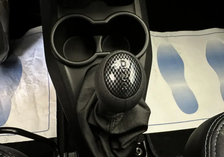 Le levier de vitesses automatique noir avec marquages D, N, R, et T dans l'habitacle d'une Aixam Ambition rouge.