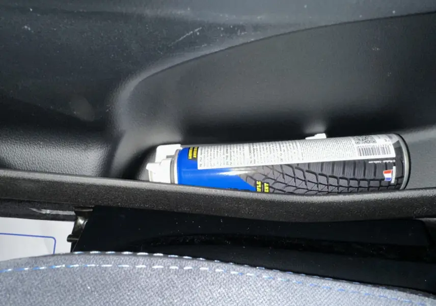 Gros plan sur le rangement intérieur côté conducteur d'une Aixam Ambition rouge 2025 avec un spray bleu posé.