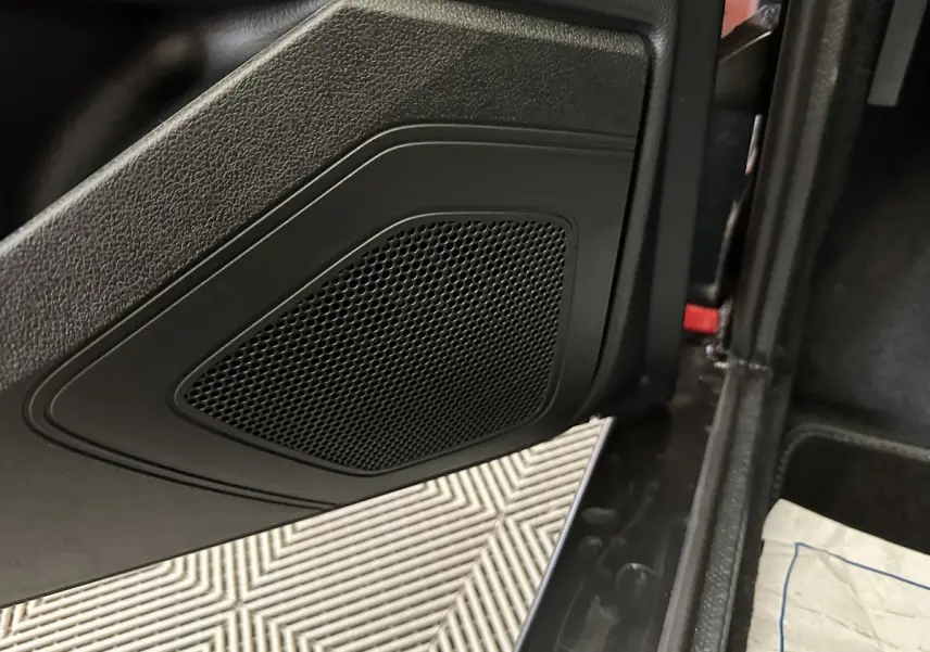 Gros plan sur la porte intérieure noire d'une Aixam Ambition rouge, mettant en valeur le haut-parleur intégré.