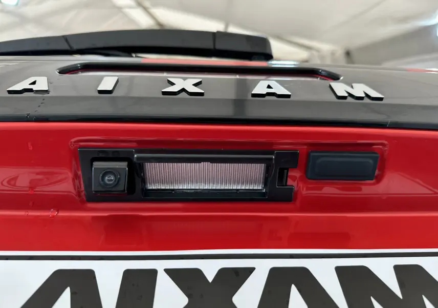Gros plan sur la caméra de recul intégrée au hayon rouge de l'AIXAM AMBITION 2025, avec logo visible.