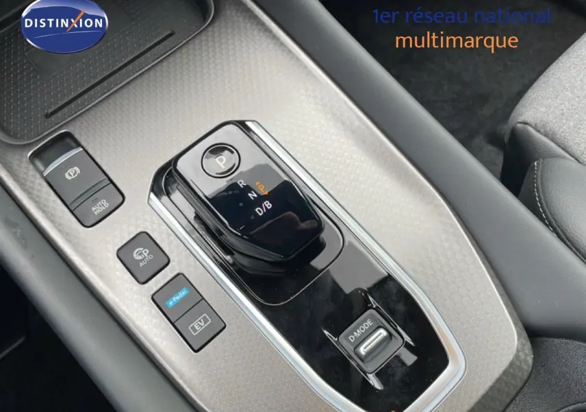 Vue rapprochée de la console centrale du Nissan Qashqai gris, mettant en valeur le levier de vitesse automatique et les boutons de contrôle.