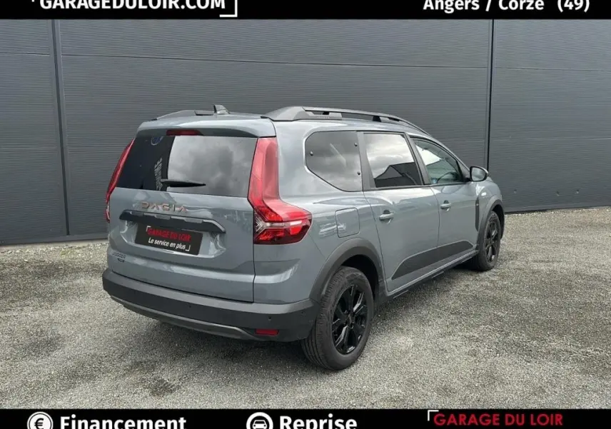 Vue 3/4 arrière droite d'un Dacia Jogger Extreme+ Hybrid 140 2025 gris avec jantes noires et barres de toit.