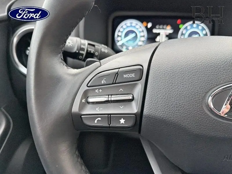 Gros plan sur les commandes du volant cuir noir d'un Hyundai Kona Cyber Grey Métal, avec tableau de bord numérique en arrière-plan.