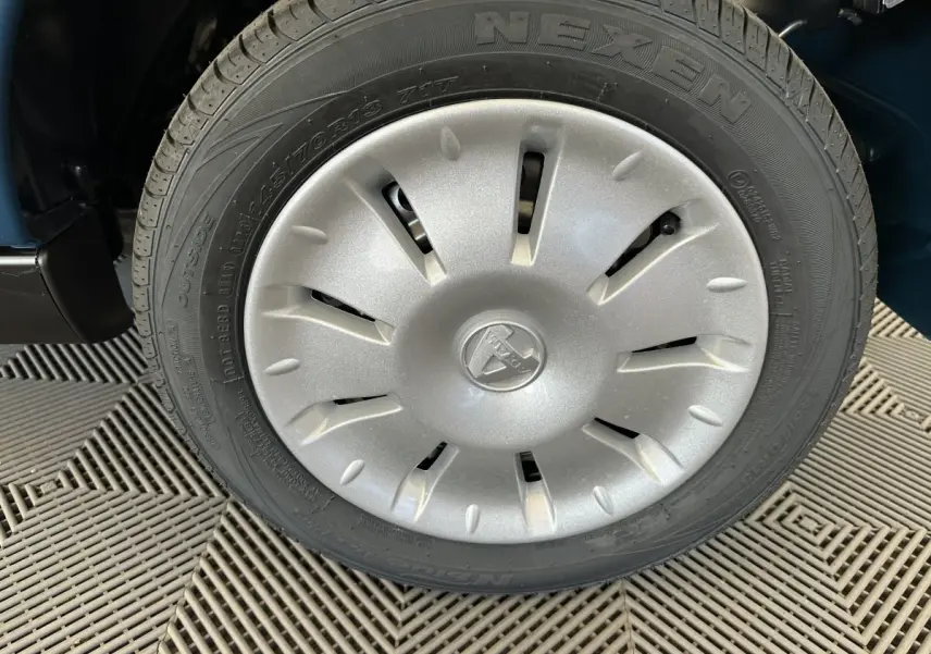 Gros plan sur la roue avant droite de l'AIXAM AMBITION 0.5 CITY PACK bleu avec enjoliveur argenté et logo central.