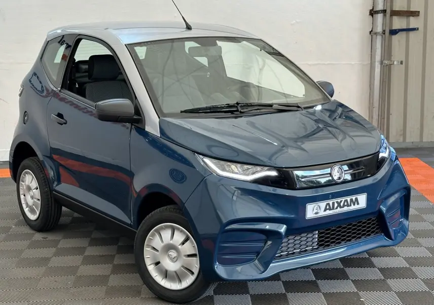 Vue 3/4 avant d'une Aixam Ambition 0.5 City Pack bleu avec rétroviseur caméra côté gauche et jantes argentées.