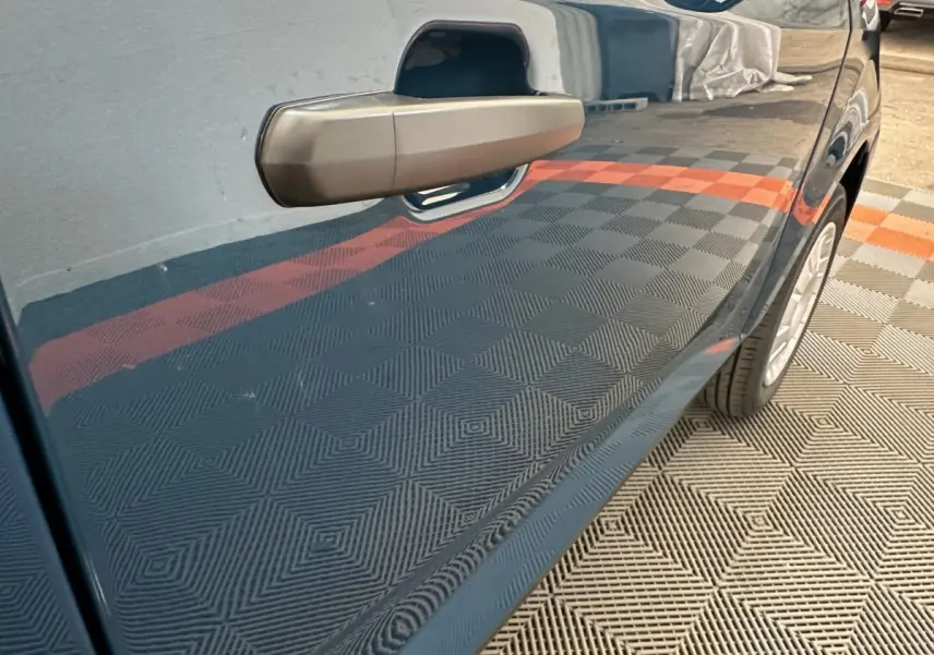 Gros plan sur la portière côté conducteur d'une Aixam Ambition bleu 2025 avec rétroviseur caméra intégré.