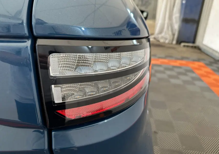 Gros plan sur le feu arrière droit bleu de l'AIXAM AMBITION 0.5 CITY PACK 2025 avec détails lumineux distinctifs.