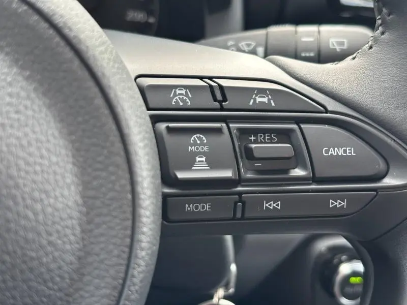 Gros plan sur les commandes de régulateur de vitesse au volant d'une Toyota Yaris blanche hybride 2025.