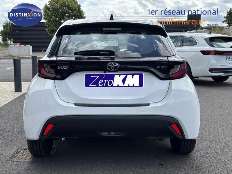 Vue arrière d'une Toyota Yaris 116h Dynamic blanche de 2025 avec hayon noir et feux arrière sombres.