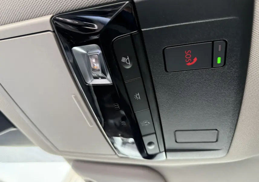 Vue en gros plan du panneau de commandes de toit intérieur gris clair avec bouton SOS rouge et éclairage sur Nissan Qashqai gris squale métal.