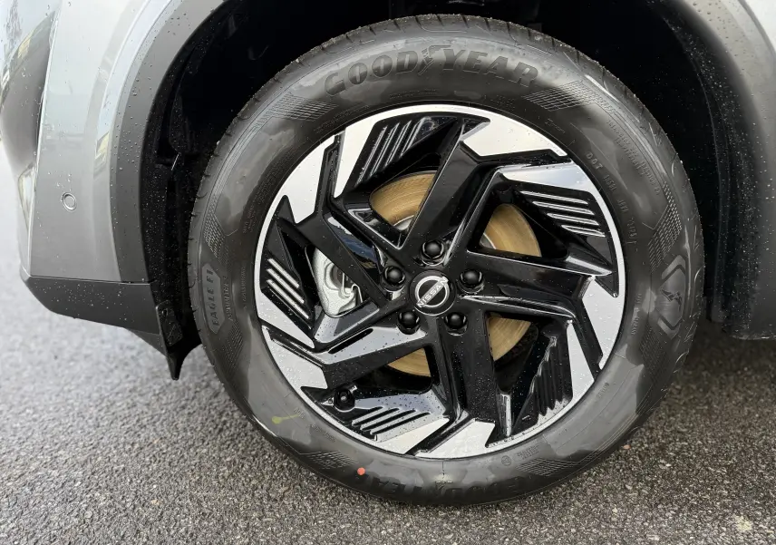 Gros plan sur la roue avant gauche du Nissan Qashqai 2025 gris squale métal avec jante noire et argentée au design moderne.