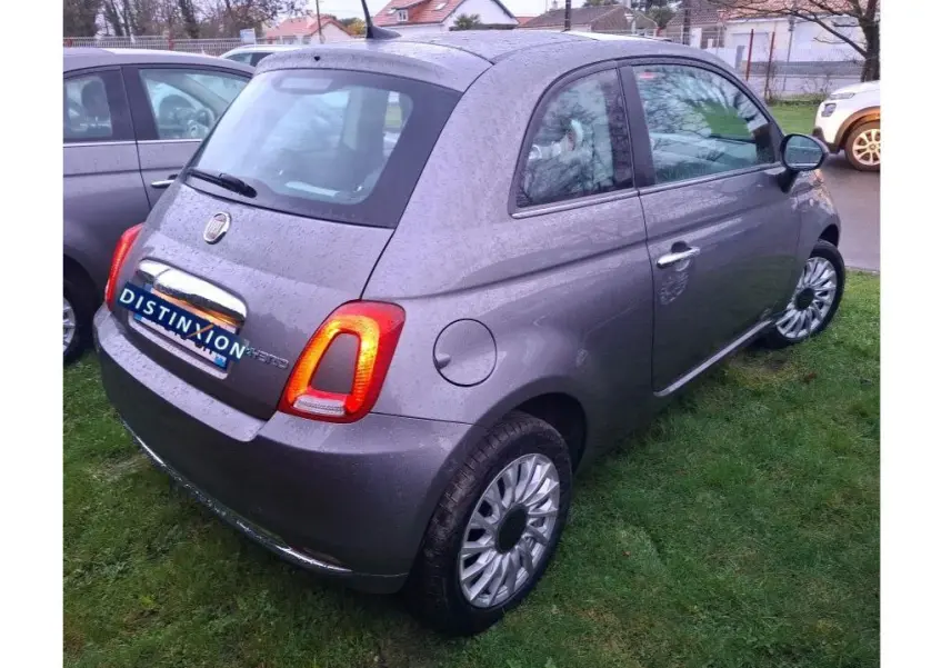 Vue 3/4 arrière droite d'une Fiat 500 gris Electroclash 2022 avec feux arrière allumés sur pelouse humide.