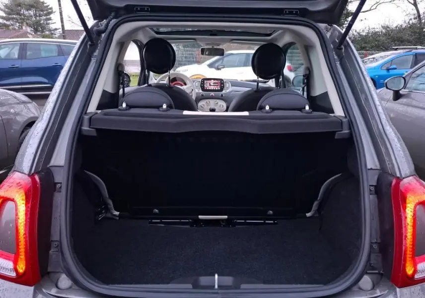 Vue arrière ouverte sur le coffre d'une FIAT 500 gris Electroclash avec intérieur et tableau de bord visibles.