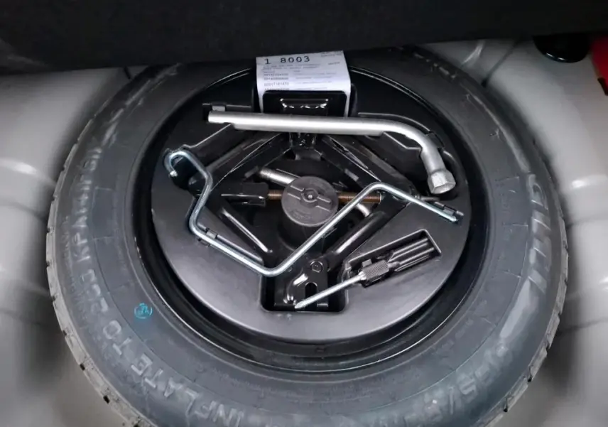 Gros plan sur la roue de secours et les outils de bord dans le coffre d'une FIAT 500 Gris Electroclash 2022.