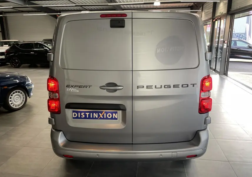 Vue arrière du Peugeot Expert Fourgon gris Artense avec portes battantes et feux allumés en intérieur showroom.