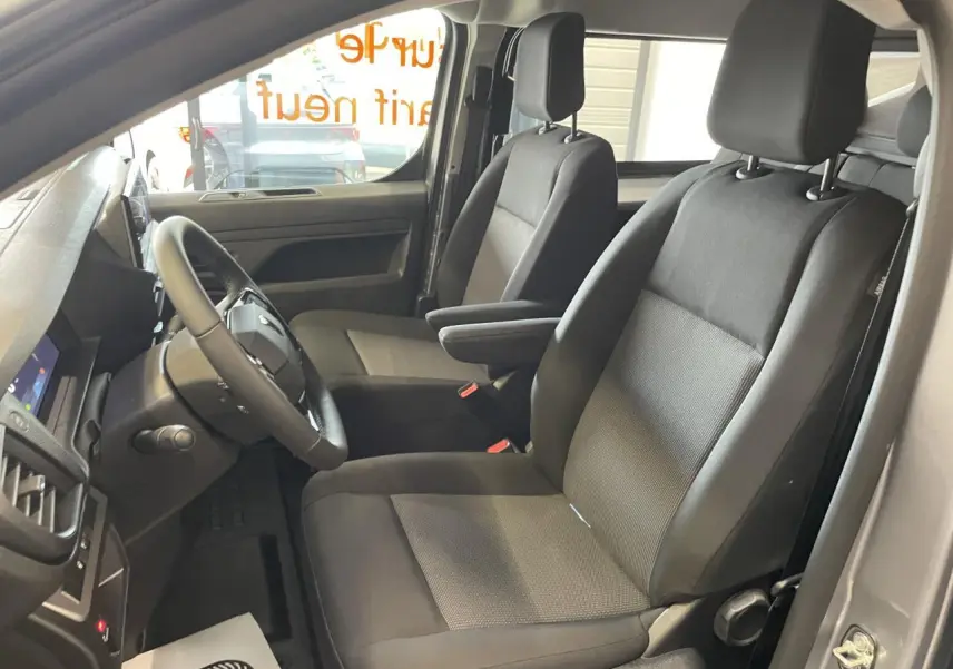Vue intérieure côté conducteur du Peugeot Expert Fourgon gris Artense, montrant les sièges avant noirs et le volant multifonction.