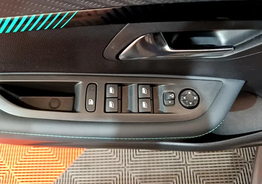 Vue rapprochée de la porte côté conducteur d’une Peugeot 208 gris foncé, avec commandes électriques des vitres et rétroviseurs.