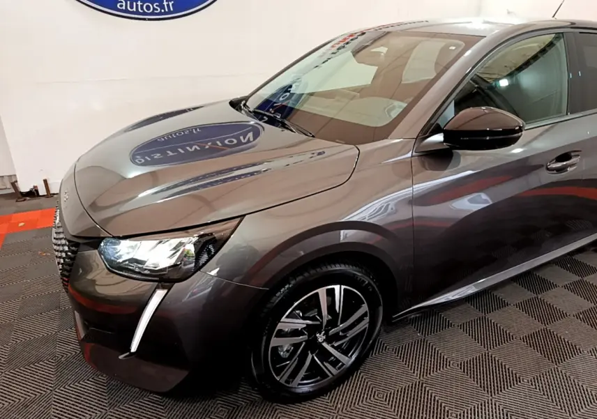 Peugeot 208 gris foncé vue en 3/4 avant droit, mettant en valeur ses phares LED et jantes alliage distinctives.