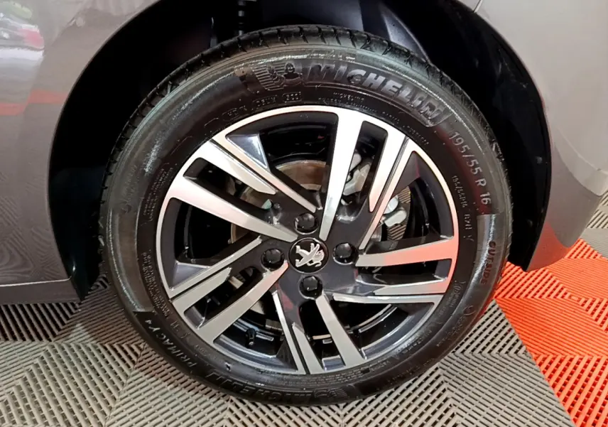 Gros plan sur la roue avant droite gris foncé d'une Peugeot 208 PureTech 100 avec jante alliage bicolore.