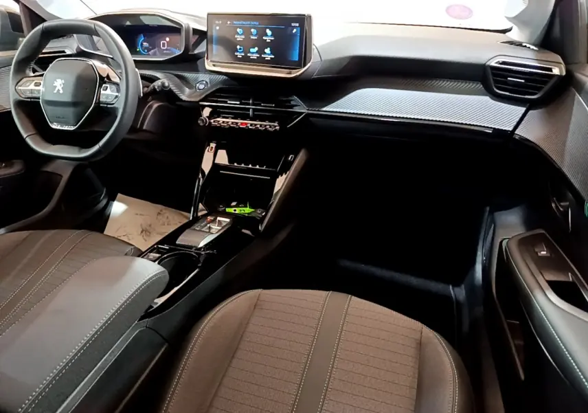 Vue intérieure avant droite du Peugeot 208 2022, tableau de bord noir avec écran tactile central et volant cuir multifonctions.