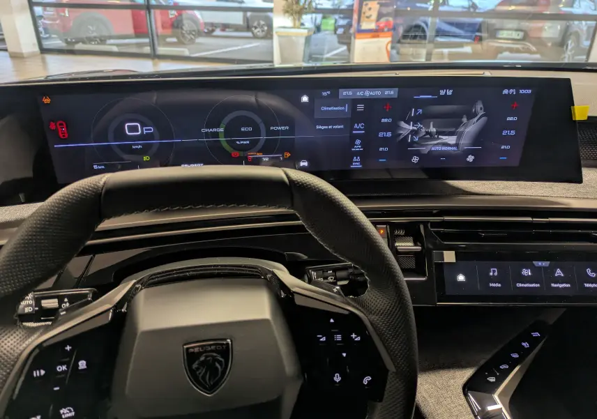 Vue intérieure centrée sur le tableau de bord et le volant noir du Peugeot 3008 Hybrid 145 GT, avec écran digital large.