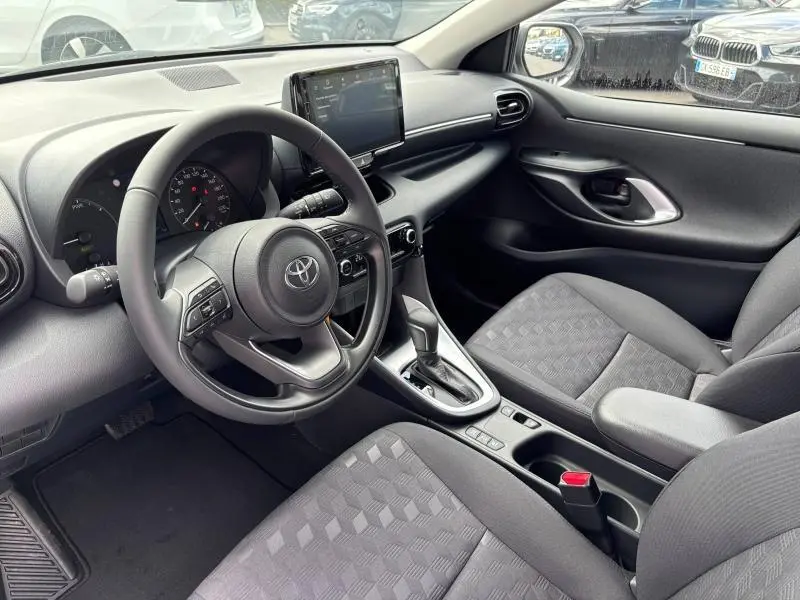 Vue intérieure côté conducteur de la Toyota Yaris 116h Dynamic 2025, volant multifonction et écran tactile central visibles.