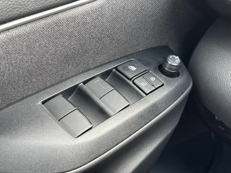 Gros plan sur les commandes de lève-vitres et rétroviseurs côté gauche intérieur de la Toyota Yaris 116h Dynamic blanche 2025.