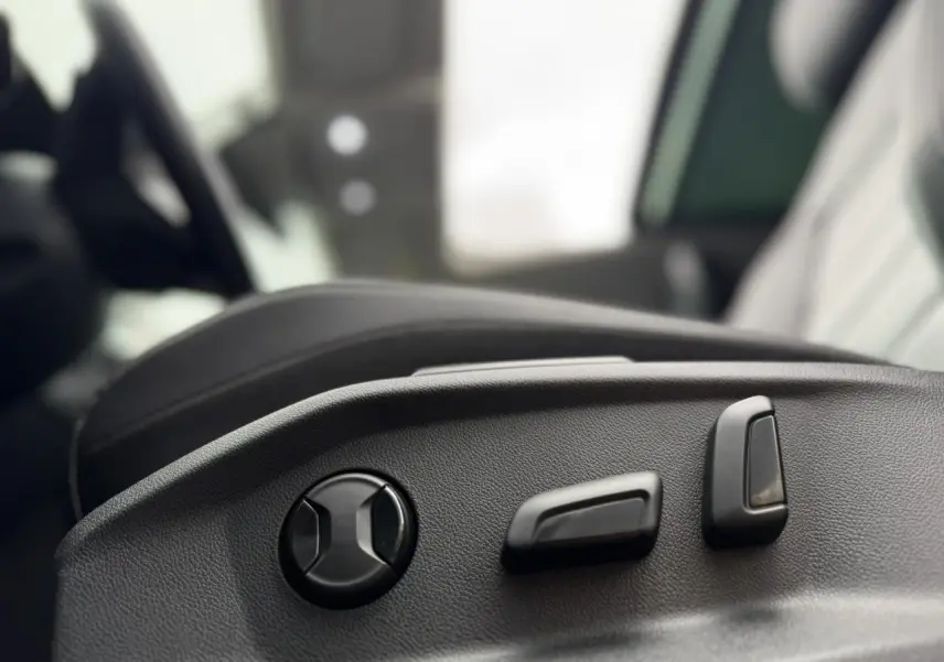 Gros plan sur les commandes électriques de réglage du siège conducteur du Volkswagen T-Roc 1.5 TSI argent Pyrite.