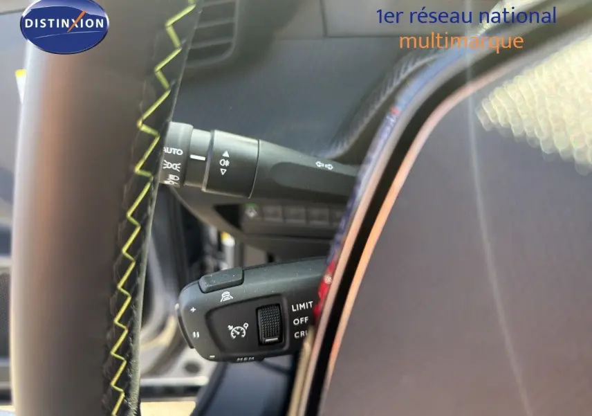 Détail du volant avec commandes de régulateur et commodo d’éclairage dans un Peugeot 2008 gris Artense toit noir.