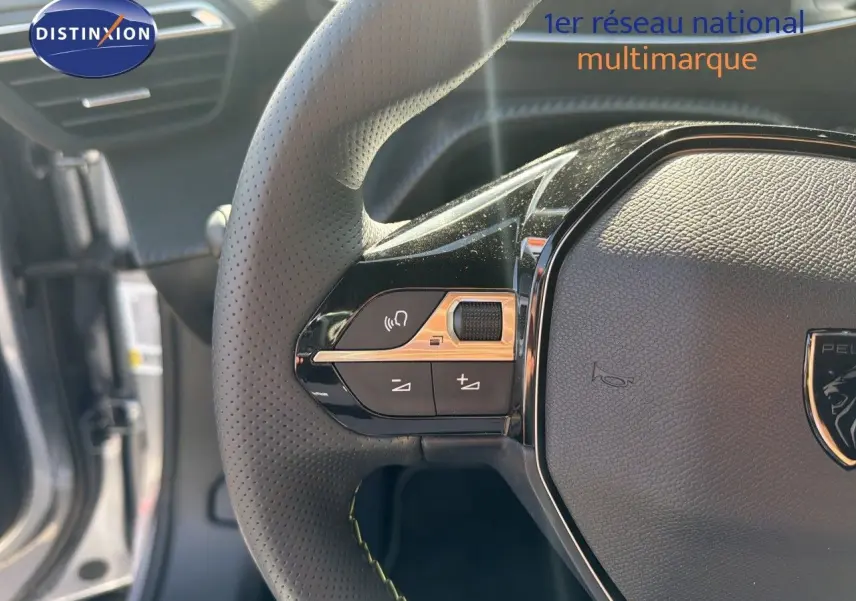 Gros plan sur le volant cuir perforé du Peugeot 2008 1.2 Hybrid 145 GT, avec commandes intégrées et logo central.