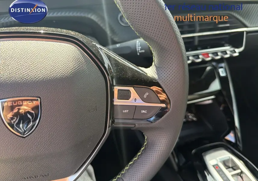 Gros plan sur le volant perforé de la Peugeot 2008 1.2 Hybrid 145 GT avec commandes intégrées, intérieur noir.