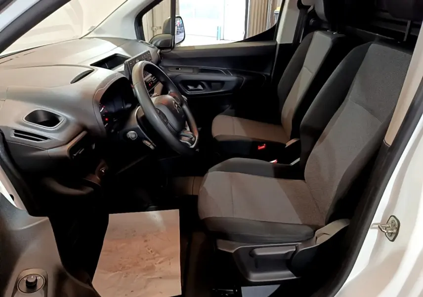 Intérieur côté conducteur du Citroën Berlingo blanc 2021, montrant le tableau de bord et sièges en tissu gris.