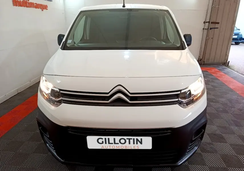 Vue frontale d'un Citroën Berlingo blanc 2021 avec phares allumés et pare-chocs noir dans un showroom.