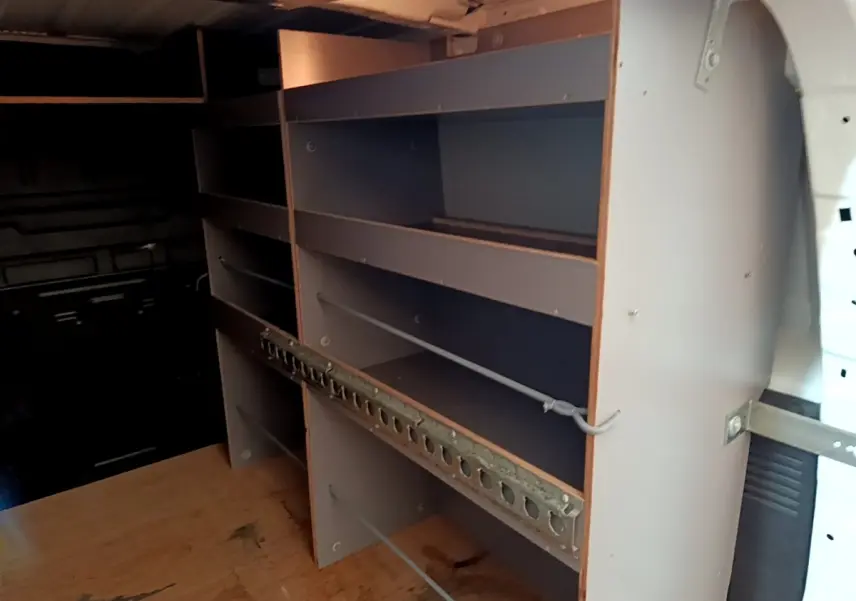 Vue intérieure du compartiment de chargement du Citroën Berlingo blanc, montrant les étagères de rangement en bois.