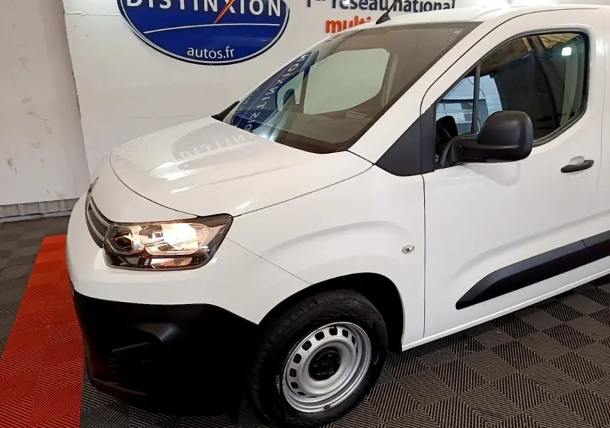 Vue 3/4 avant droit d'un Citroën Berlingo blanc avec phares allumés et jantes acier simples.