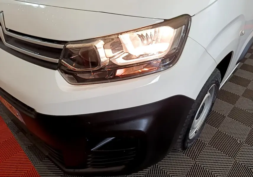 Gros plan sur l'avant droit d'un Citroën Berlingo blanc 2021 avec phare allumé et pare-chocs noir.