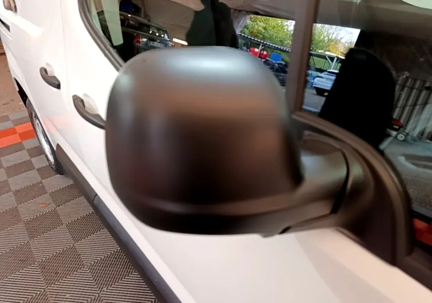 Rétroviseur noir en gros plan côté gauche d'un Citroën Berlingo blanc, vue latérale avant du véhicule.