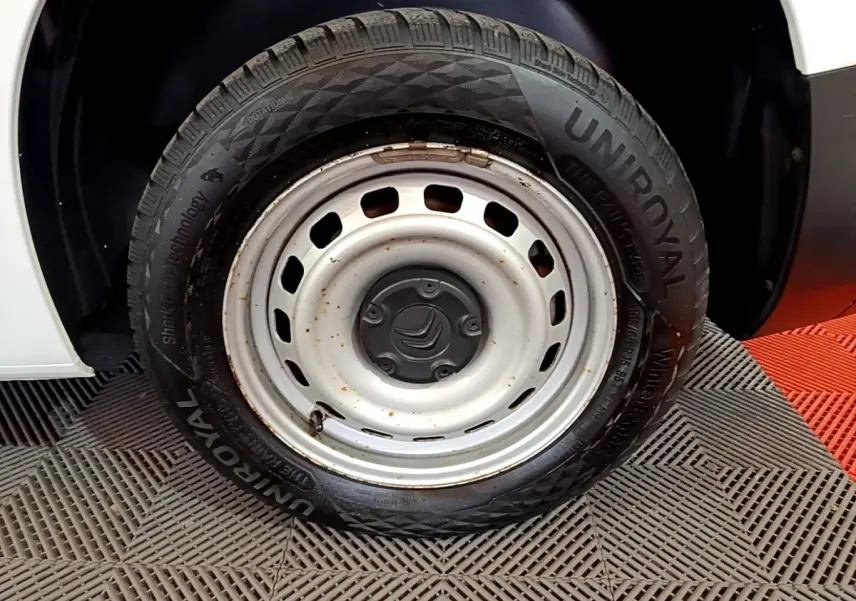 Gros plan sur la roue acier blanche et pneu Uniroyal d'un Citroën Berlingo blanc, partie arrière droite visible.