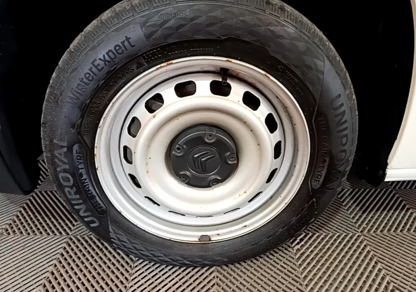 Gros plan sur la roue avant droite blanche du Citroën Berlingo 2021, avec jante acier et logo Citroën au centre.