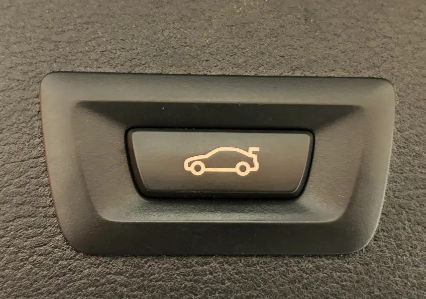 Bouton noir avec icône lumineuse orange représentant l'ouverture du coffre d'un BMW X3 sDrive18dA 2017.