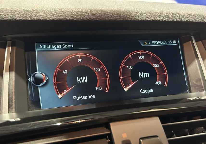 Affichage numérique intérieur du tableau de bord BMW X3 noir, montrant la puissance en kW et le couple en Nm en mode Sport.