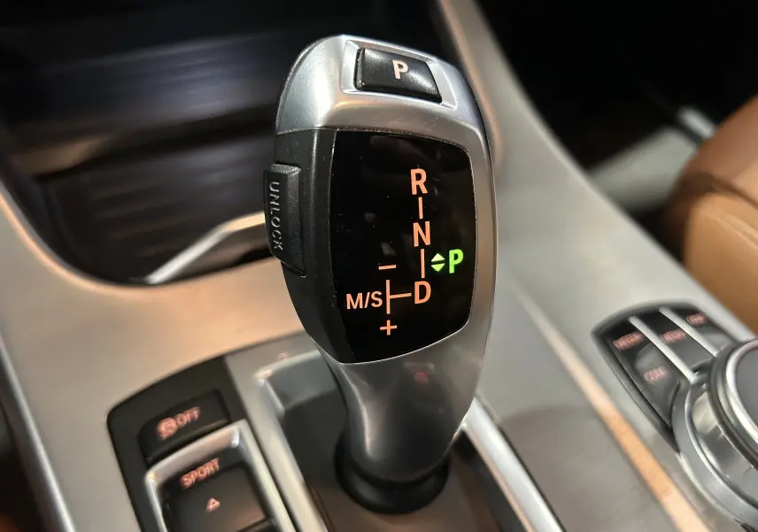 Gros plan sur le levier de vitesses automatique de la BMW X3 noir, avec indication du mode parking allumé.