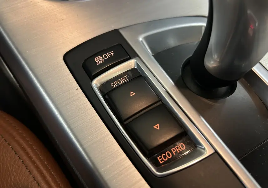 Gros plan sur les commandes de mode de conduite SPORT et ECO PRO dans l’habitacle cuir marron d’un BMW X3 noir.
