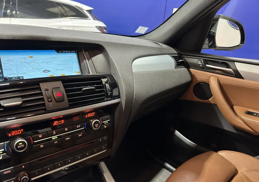 Vue intérieure côté passager de la BMW X3 2017 avec tableau de bord noir et sellerie cuir marron.