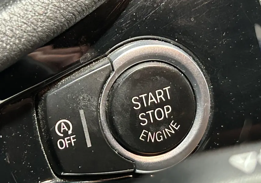 Gros plan sur le bouton noir Start Stop Engine et la commande d'arrêt du système auto start/stop dans l'habitacle d'un BMW X3.