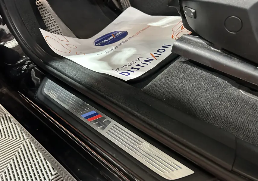 Détail de la plaque de seuil de porte M sur le côté gauche d’un BMW X3 noir, intérieur avec tapis et protection papier.
