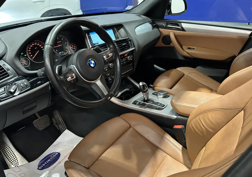 Vue intérieure côté conducteur du BMW X3 2017 avec sièges en cuir marron et tableau de bord noir.