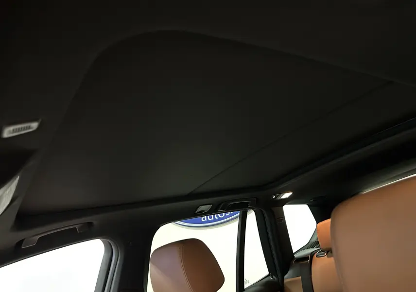 Vue intérieure du toit ouvrant et des sièges en cuir marron côté gauche d'un BMW X3 noir de 2017.
