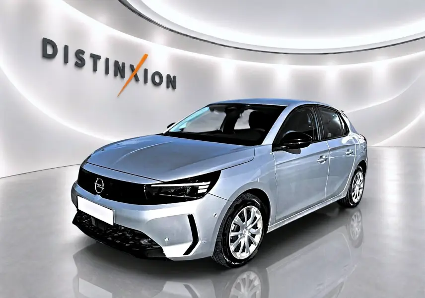 Opel Corsa gris alu vue 3/4 avant droit, avec calandre noire et jantes alliage visibles dans un showroom lumineux.
